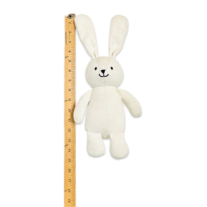White plush bunny toy next to a ruler on a white background