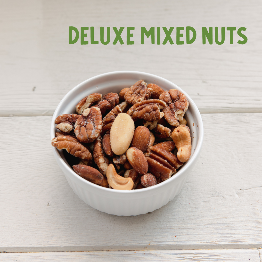 Bowl of deluxe mixed nuts on a light wooden surface with &
