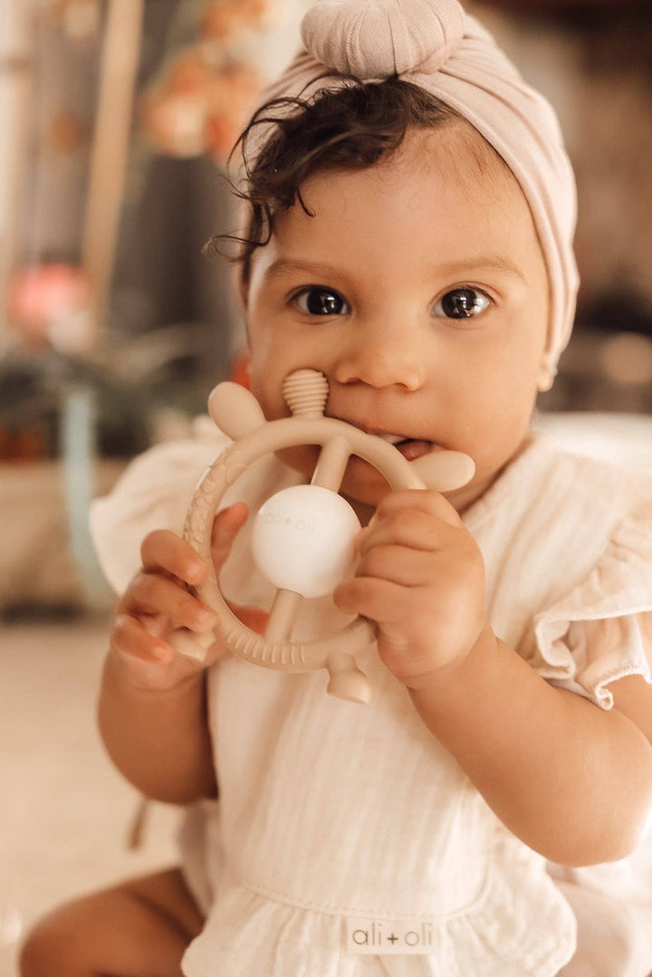 Baby holding a teething ring with a blurred background