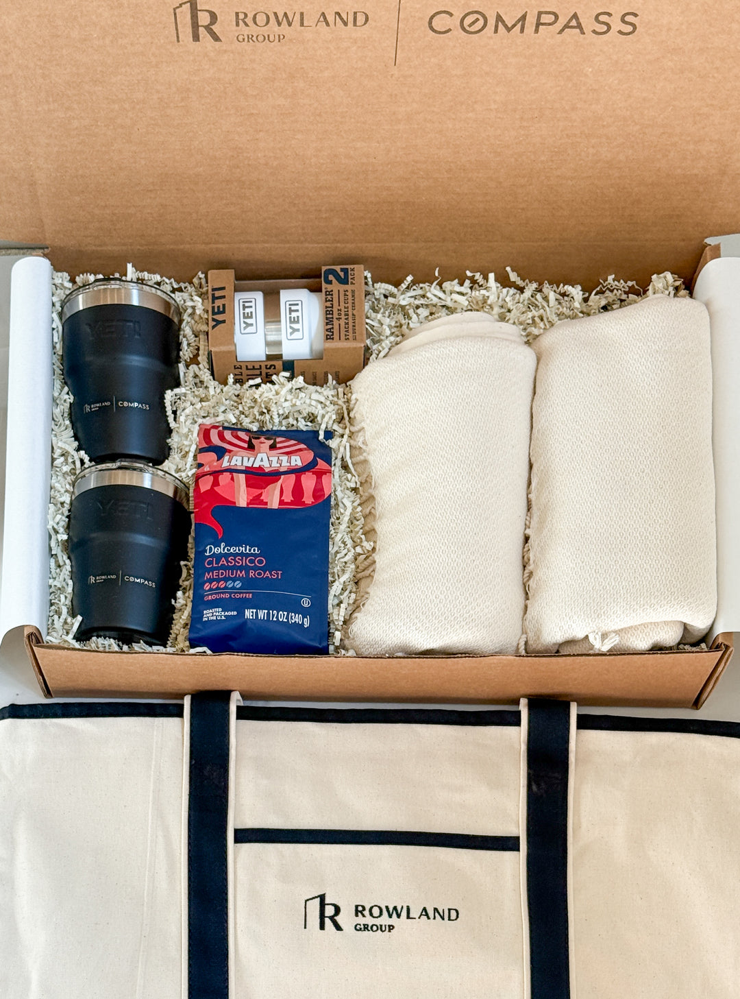 Gift set with two black tumblers, a bag of coffee, 2 espresso cups, a tote bag and two white towels in a branded box.
