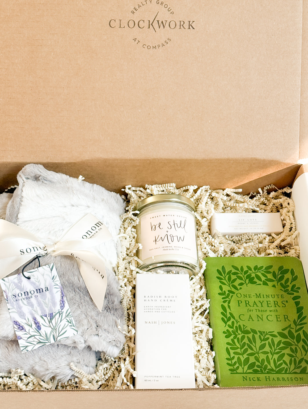 Gift box with a candle, hand cream, a blanket, a prayer book and and lip care on a beige background