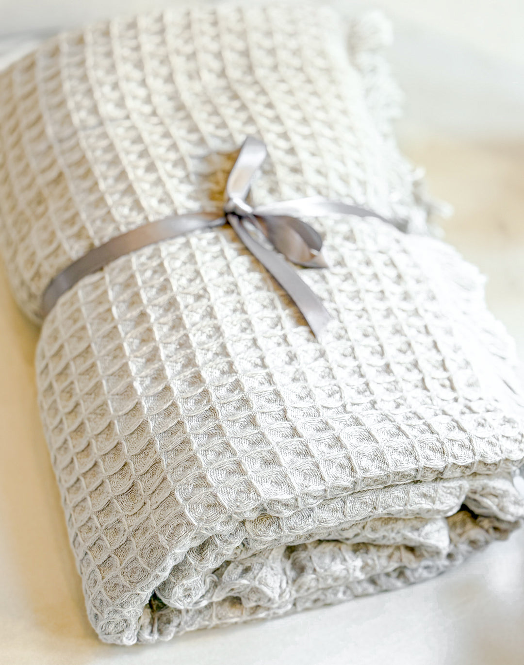 Folded textured blanket with a ribbon on a light background