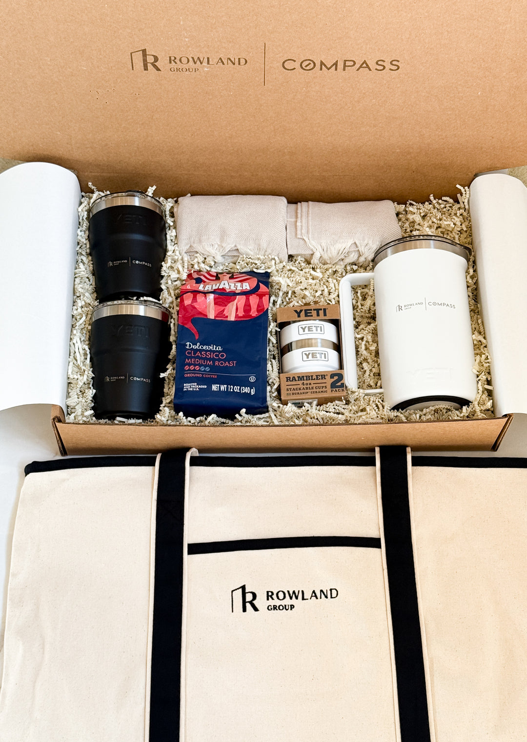 Gift set with Rowland Group branding including mugs, blankets, French press, coffee beans, and a tote bag.