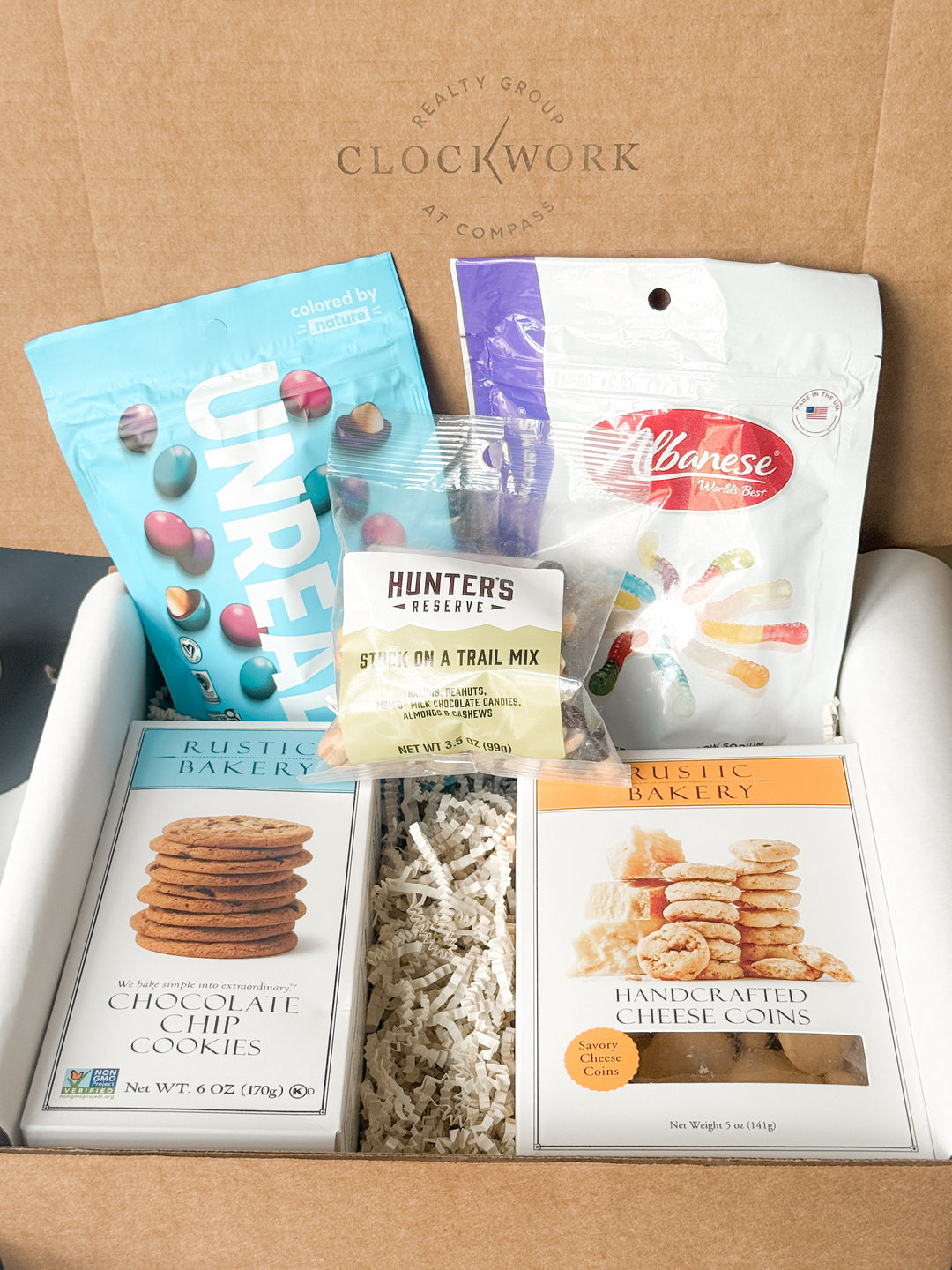 Assorted snacks and cookies in a box with Clockwork branding.