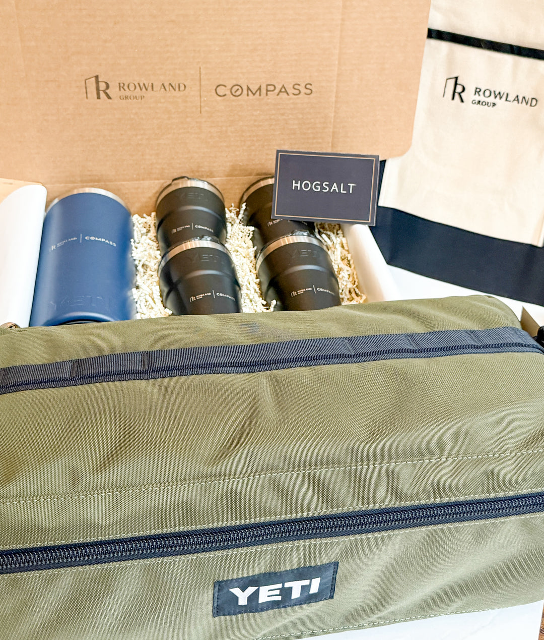 Tumblers and bags packaged with Rowland Rhodes, Compass, and YETI branding.