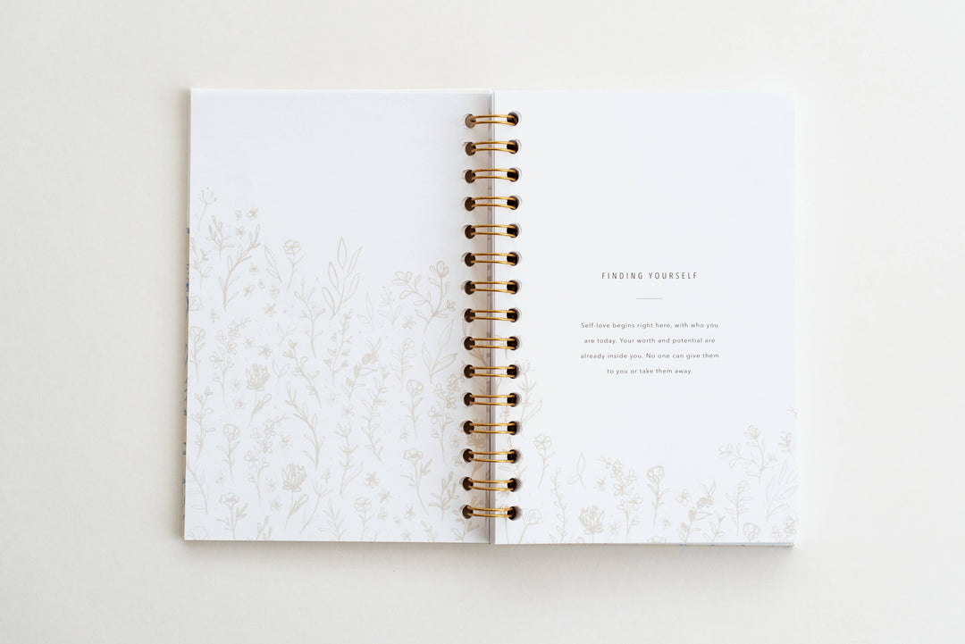 Open notebook with marble cover and gold spiral binding on a light background