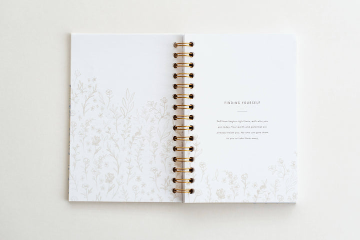 Open notebook with marble cover and gold spiral binding on a light background