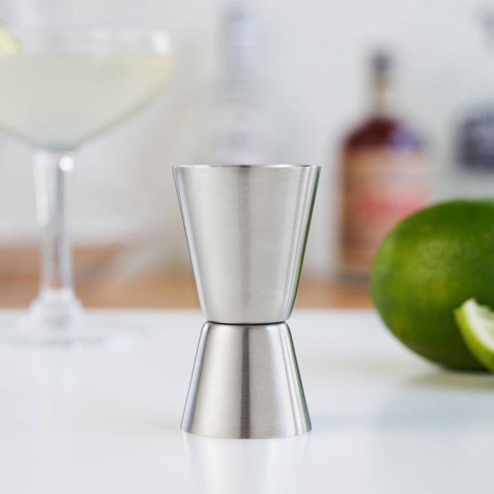 Metallic jigger on a kitchen counter with a blurred background
