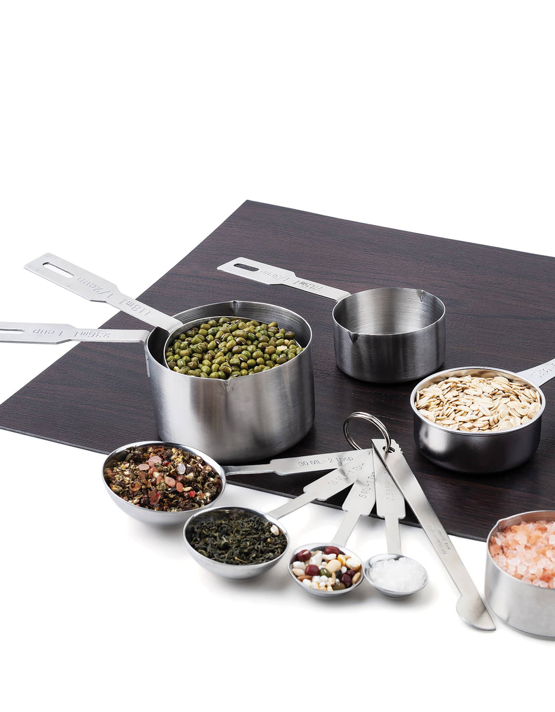 Various measuring cups and spoons filled with herbs and spices on a wooden surface with a white background. 