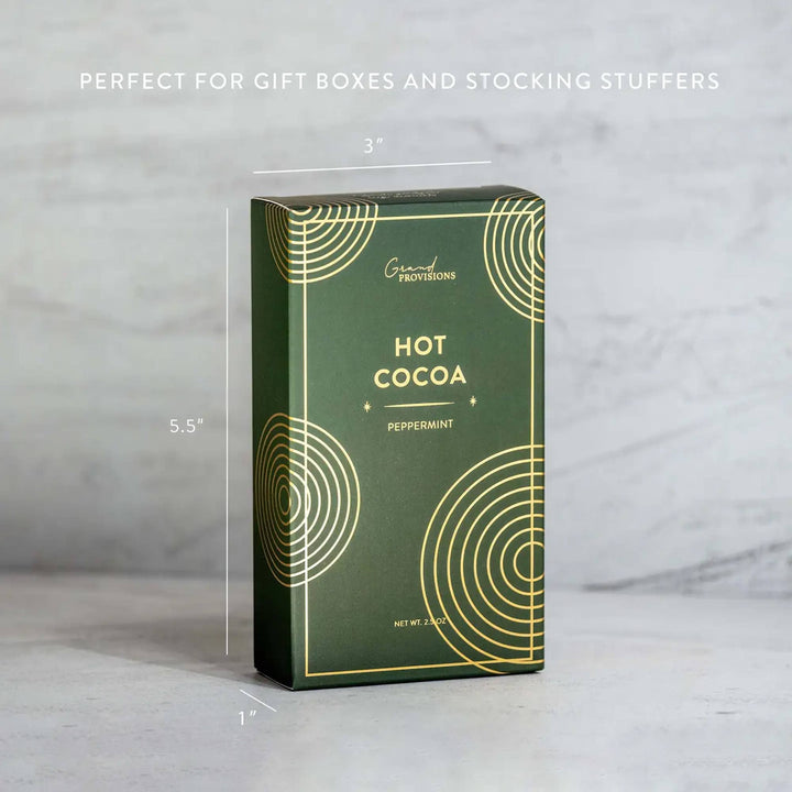 Green hot cocoa packaging with dimensions and decorative elements on a gray background