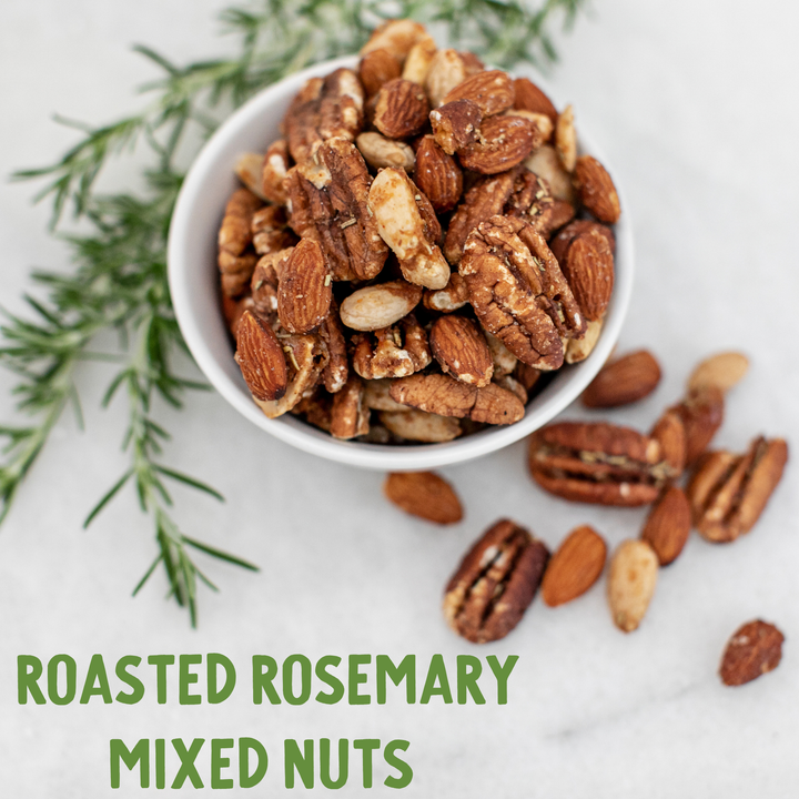 Roasted rosemary mixed nuts in a white bowl with rosemary sprigs on a light background