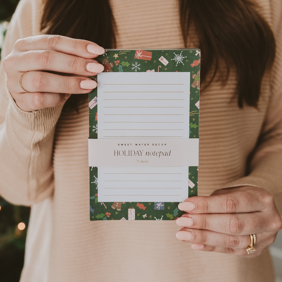 Person holding a holiday-themed notepad with decorative cover