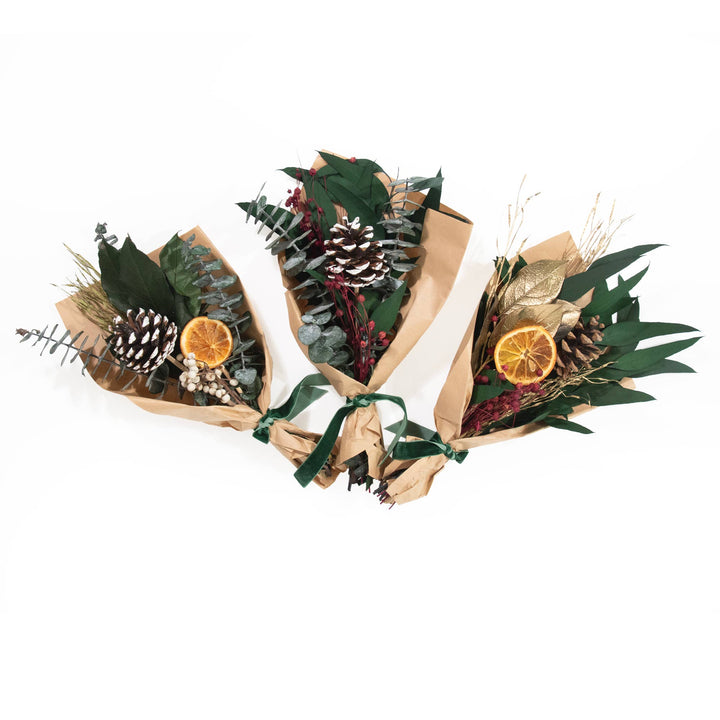 Three festive flower bouquets with greenery, pinecones, and oranges on a white background