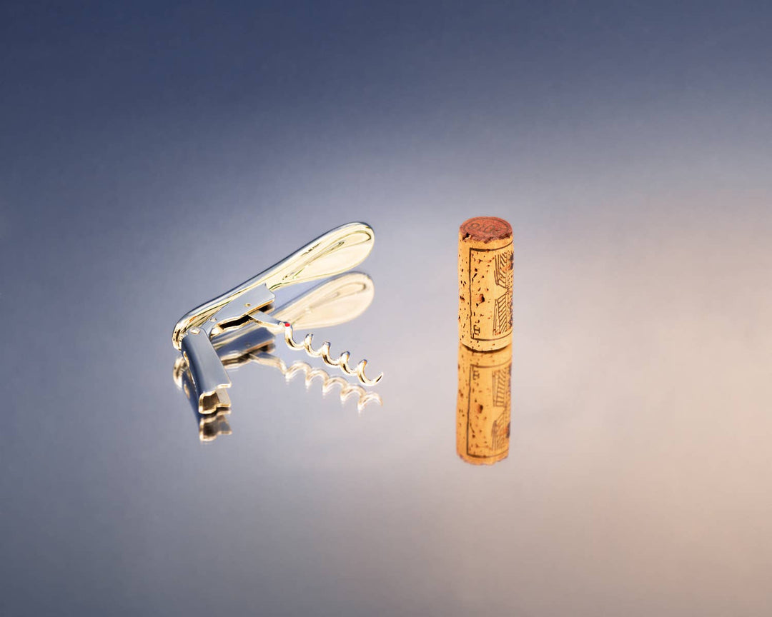Metal wine opener and cork on a gradient blue background