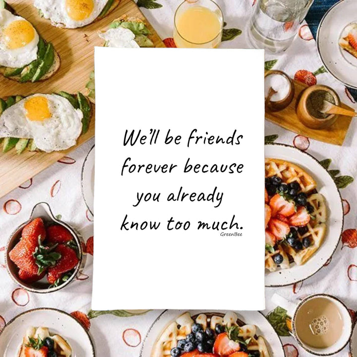 Table with various breakfast items and a white dish towel with a friendship quote.