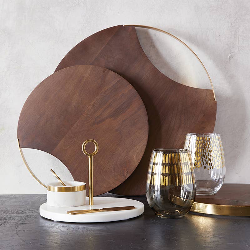 Wooden cutting boards, glassware, and a marble bowl on a dark surface with a light gray background.
