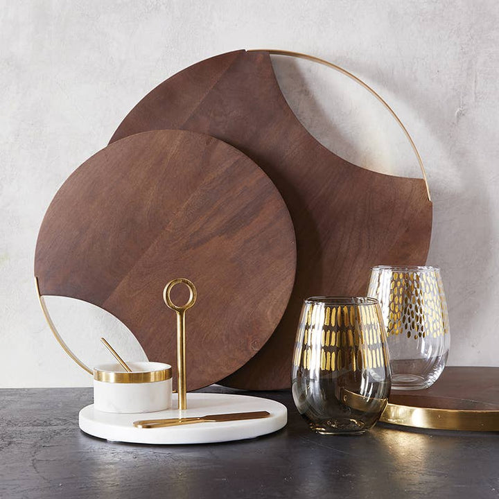 Wooden cutting boards, glassware, and a marble bowl on a dark surface with a light gray background.