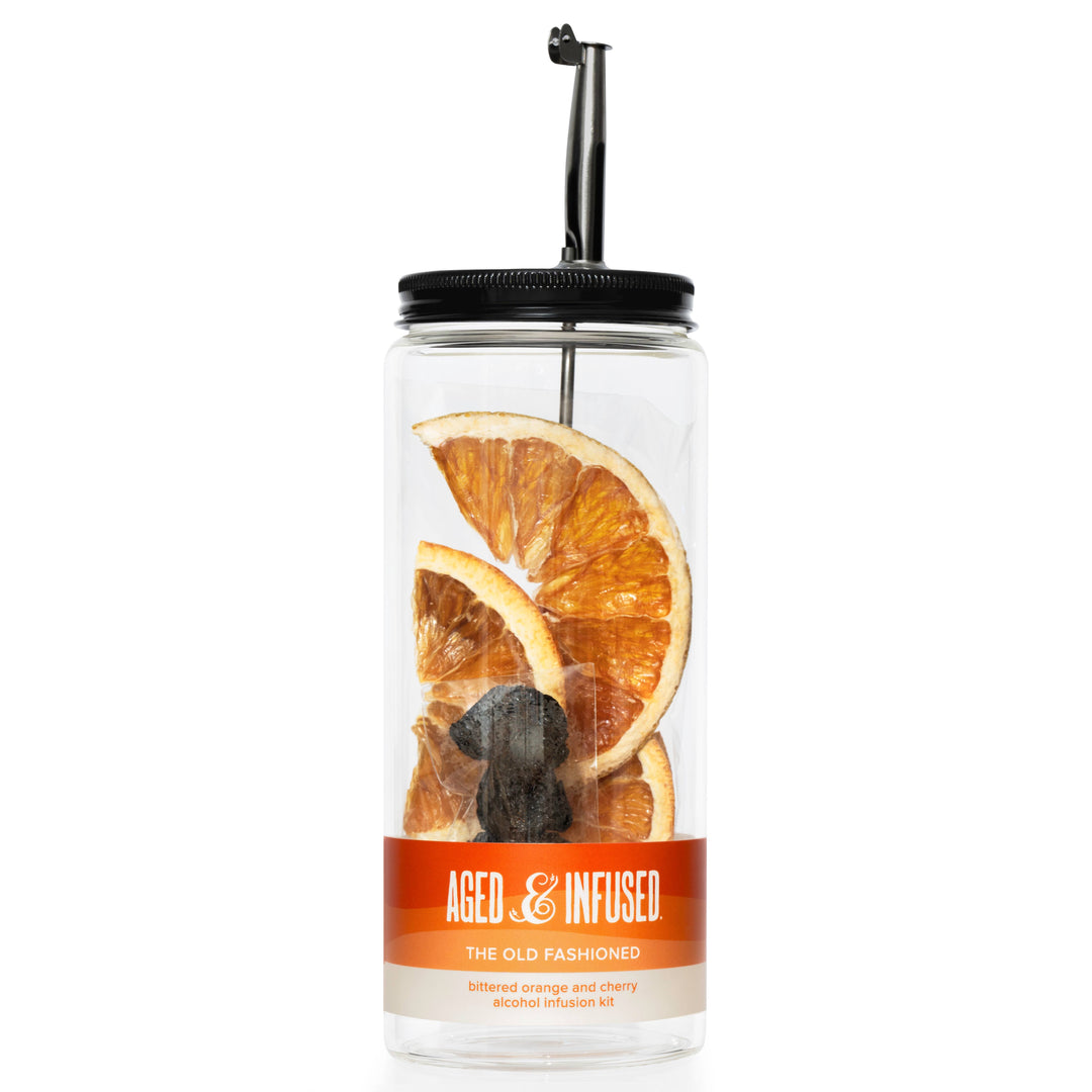 Clear glass bottle of Old Fashioned mix with orange slices and a black lid on a white background