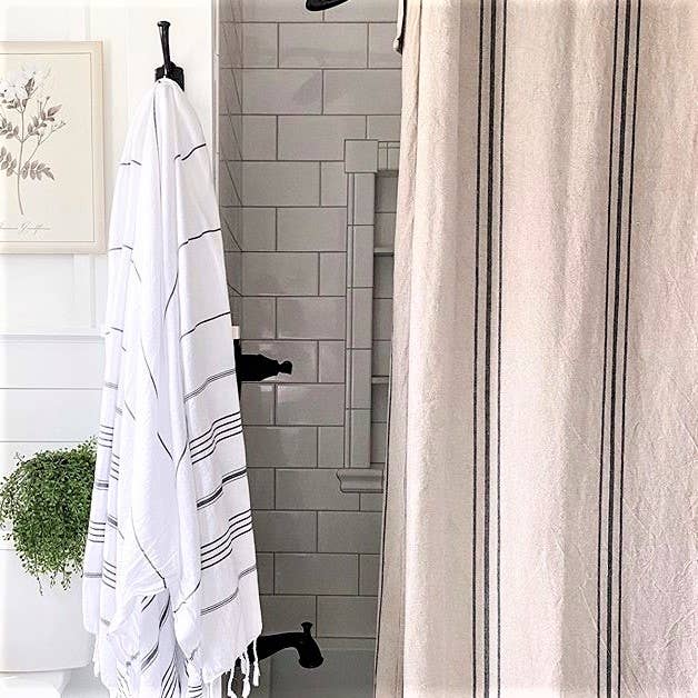 Bathroom with striped towel and shower curtain, featuring a plant and framed picture.