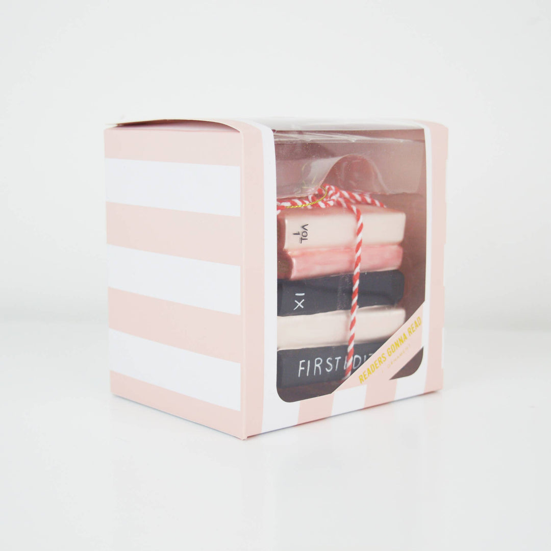 Ornament in a clear box with pink and white striped design on a light gray background