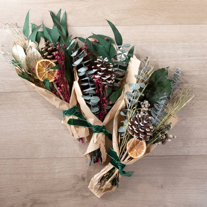 Bouquets of dried flowers and pinecones on a wooden surface