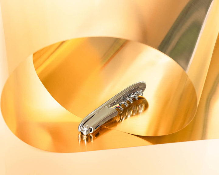 Metal wine opener on a gold background