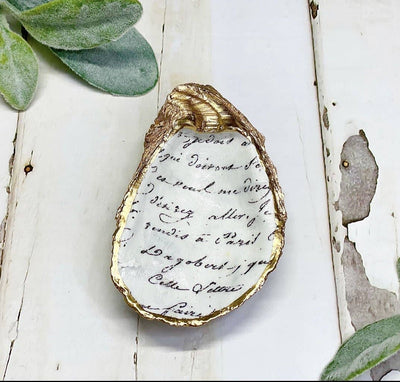 The decoupage oyster trinket dish makes a perfect catchall for your jewelry or a decor piece around your home.  Each trinket dish is handcrafted with care. The edge is trimmed in gold leaf paint with the back left natural.   The shells measure approximately 3-4+ inches in length. As these shells were created by nature, they will vary in shape and size. There will be slight variations in print with each oyster.